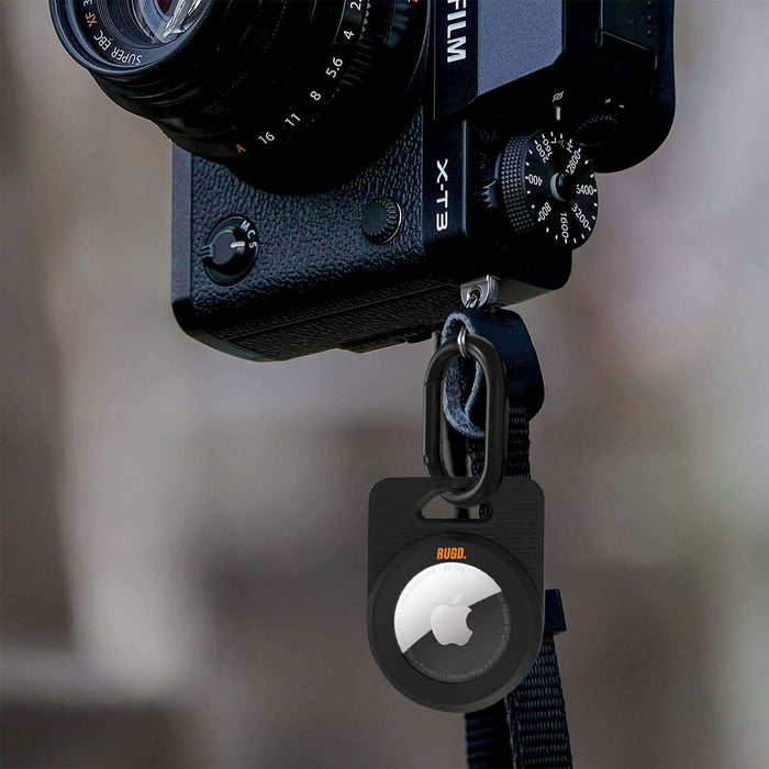 RUGD. Army Air Tag Case for Apple AirTag, attached to a camera strap for versatile use during outdoor activities.