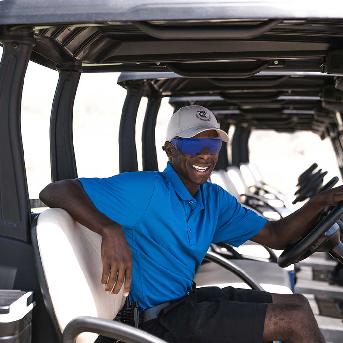 Man wearing blue golf ball finder glasses sitting in a golf cart, showcasing stylish and functional outdoor golfing gear.