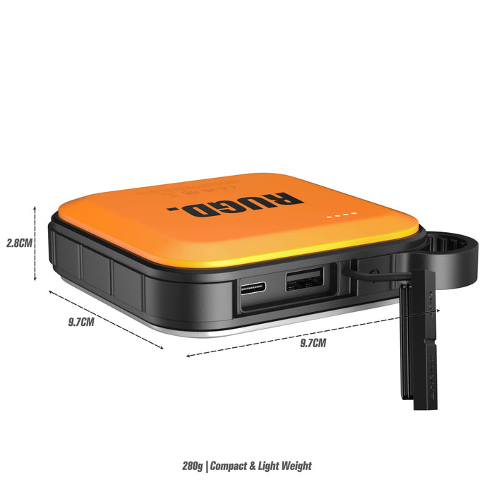 Compact orange RUGD Power Brick I Power Bank with LED camping light, USB ports, and carabiner attachment. Measures 9.7cm x 9.7cm x 2.8cm.