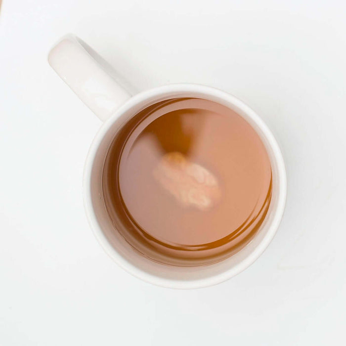 Top view of a Chewing Gum 'Prank' Mug filled with beverage, revealing a hidden gumball surprise inside.