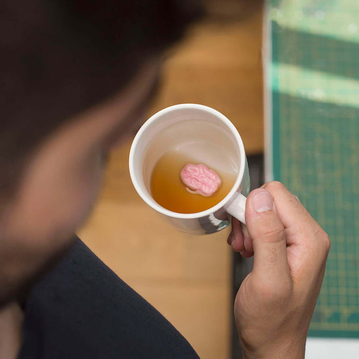 Person holding the Chewing Gum 'Prank' Mug with a hidden gumball floating in a beverage.