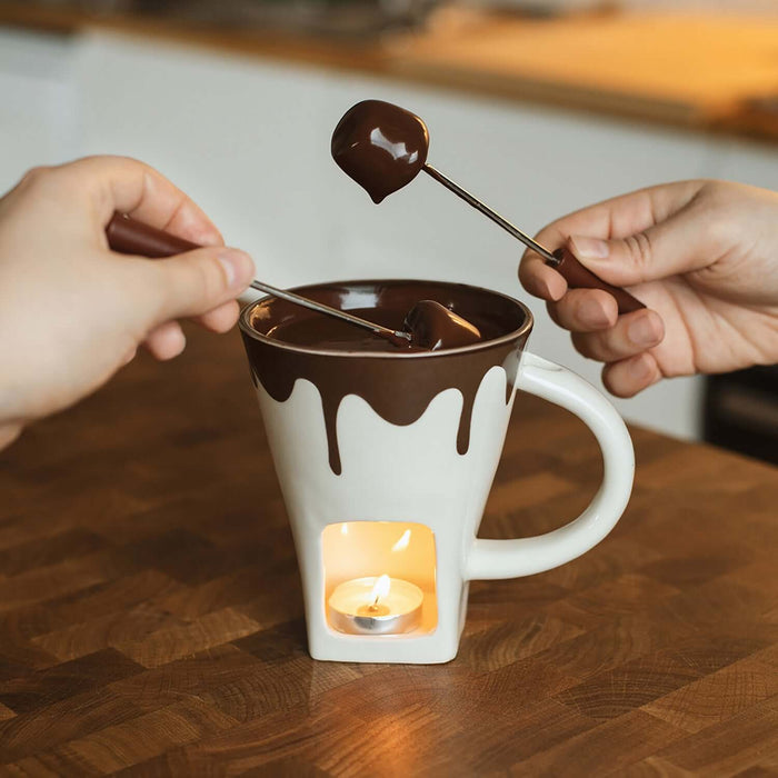 Cozy Chocolate Fondue Mug with two dipping forks and candle, perfect for melted chocolate moments.
