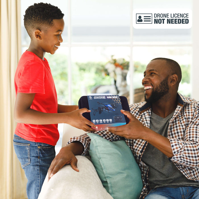 A child hands a packaged Air Chopper Drone to an adult in a cozy living room, showcasing family excitement.