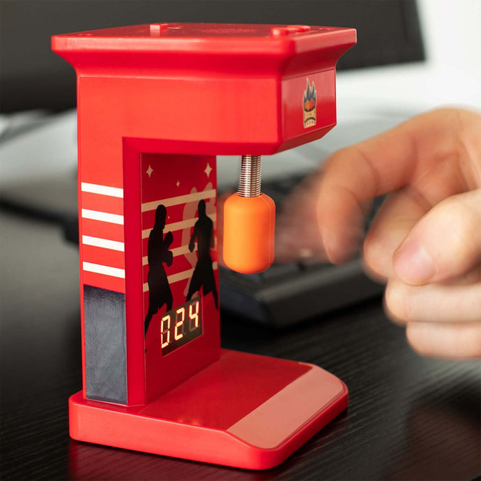 Retro mini punch bag game machine with finger-flicking gameplay, red arcade boxing design, and LED score display on a desk