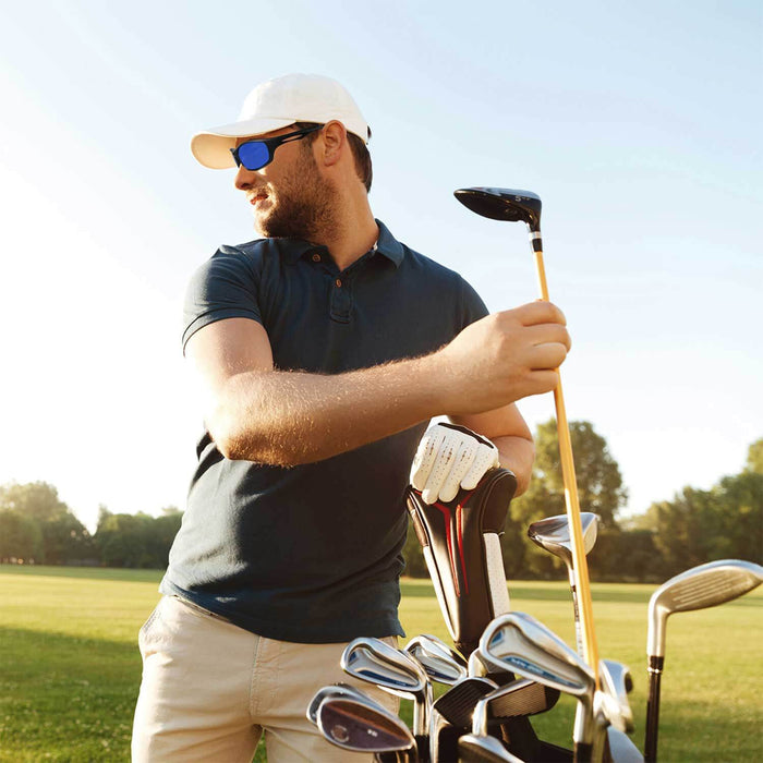 A golfer wearing blue Golf Ball Finder Glasses, preparing to swing a golf club on a sunny day in a scenic park.