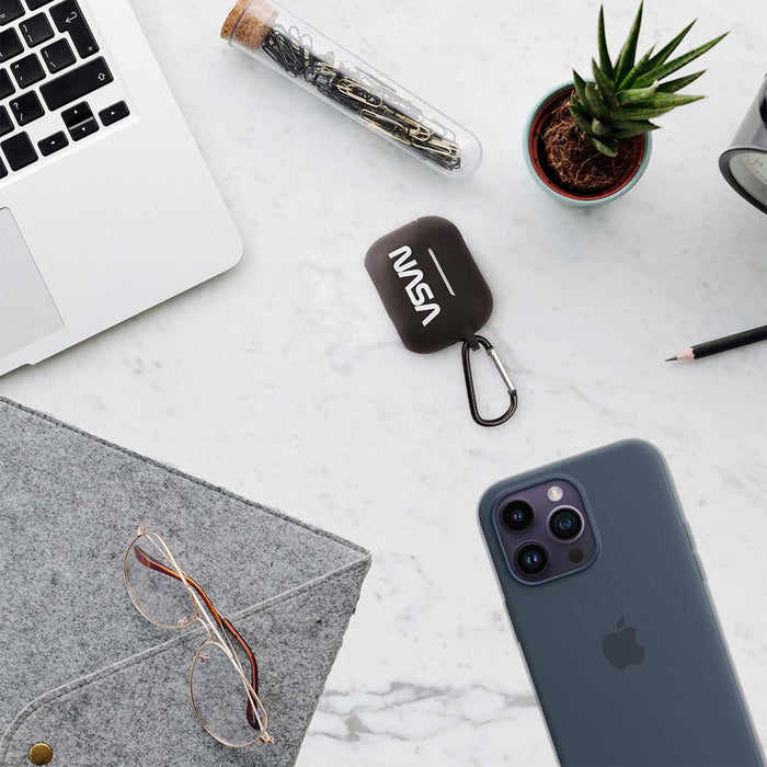 NASA Airpods Pro case with carabiner on a desk alongside a smartphone and plant.