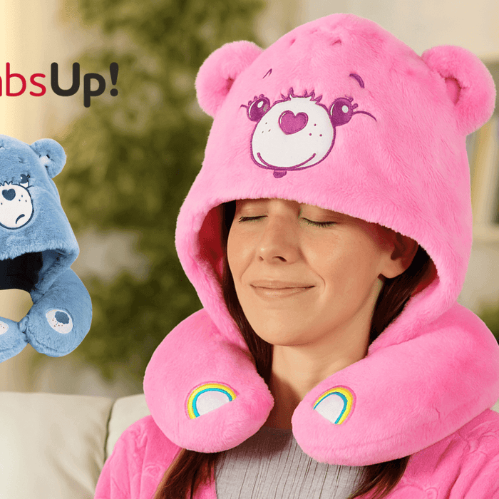 Woman wearing a pink Care Bears Snuggle Hood, enjoying comfort with a blue bear-shaped pillow beside her.