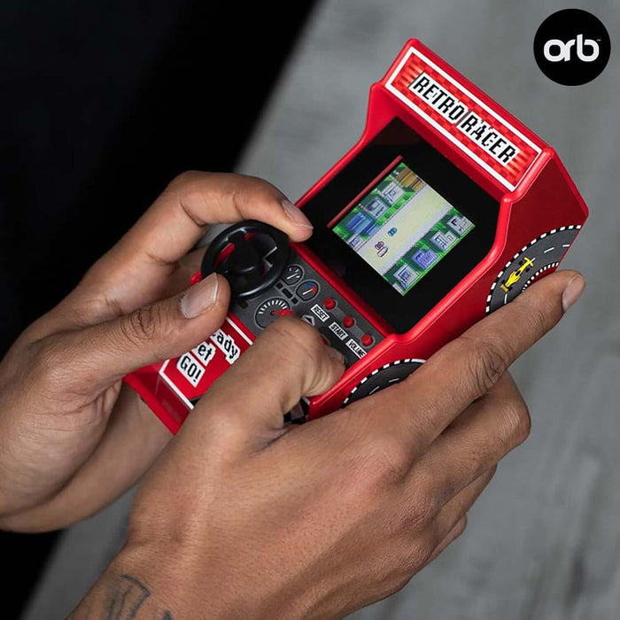 Hands playing a red Retro Mini Arcade Racing Game with a mini steering wheel, displaying classic 8-bit racing game on the screen