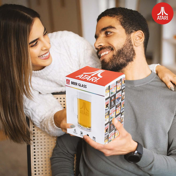 Couple smiling holding Official Atari Beer Glass in original packaging with classic Atari logo.