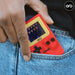 Retro Mini Handheld Games Console (150-in-1 Games) in red casing, fit comfortably in a pocket with a screen showing gameplay.