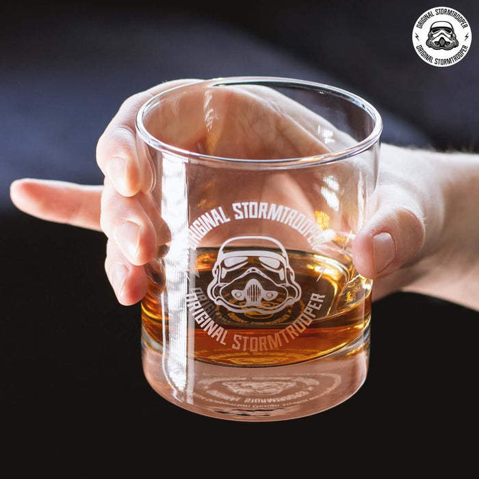 Hand holding a glass from the Original Stormtrooper 3D Helmet Decanter Set with Tray, filled with a brown drink.