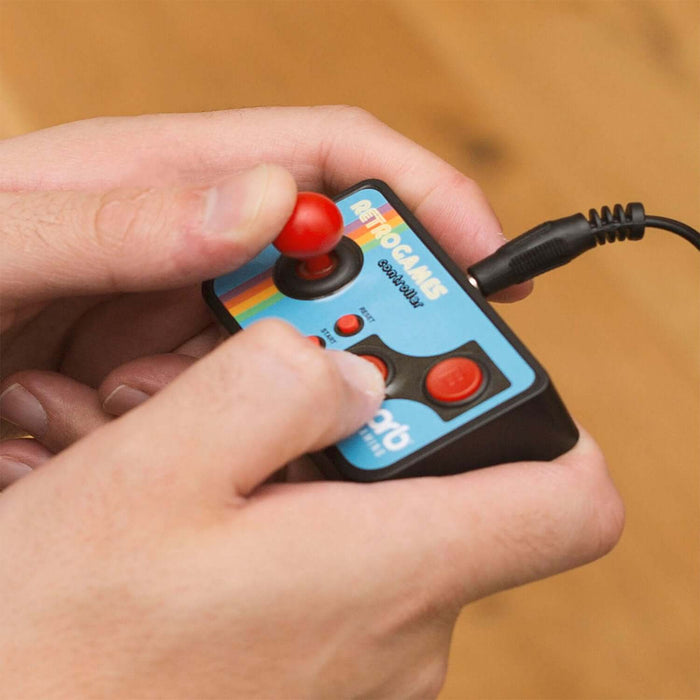 Hands holding a Plug and Play Retro Handheld Console with joystick and buttons, playing retro games on a Mini Arcade.