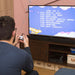 Person playing Orb Retro Mini Arcade Plug & Play TV Game on a television displaying a list of 200 retro games.