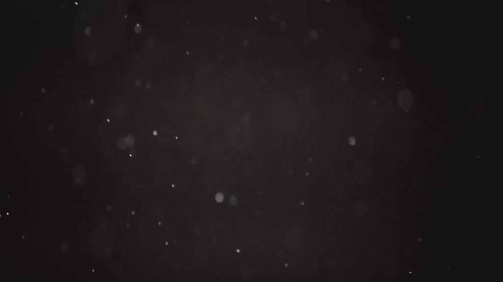 Abstract dark background with scattered light particles, creating a dreamy and atmospheric effect.
