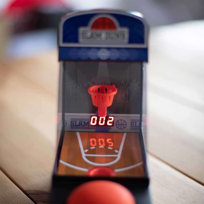 Retro mini tabletop arcade basketball game with score display, mini hoop, and orange basketball on wooden surface.