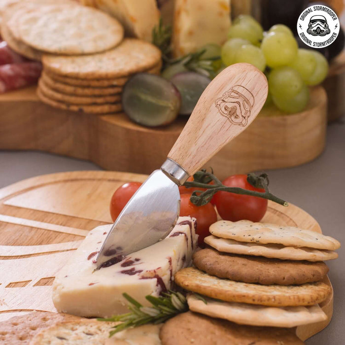 Stormtrooper cheese board with knife set, featuring iconic helmet design, surrounded by cheese, crackers, and grapes.